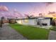 Beautiful backyard with a lush artificial lawn, modern patio seating, and stunning sunset sky at 8341 E Hubbell St, Scottsdale, AZ 85257