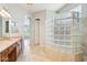 Bathroom featuring a glass block shower, dual vanities and tile flooring with an open view to bedroom area at 8664 W Yukon Dr, Peoria, AZ 85382