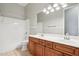 Bathroom featuring a double sink vanity with wood cabinets, a large mirror, and a shower/tub combo at 8664 W Yukon Dr, Peoria, AZ 85382