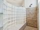 A modern glass-block shower stall, next to a stone tile shower wall with modern fixtures at 8664 W Yukon Dr, Peoria, AZ 85382