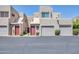 Townhome featuring desert landscaping, a red front door, and a one-car garage in a stucco complex at 11260 N 92Nd St # 2054, Scottsdale, AZ 85260