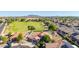 Expansive aerial view of a home near a green field and park in a well-maintained community with mountain views at 1443 N Poppy St, Casa Grande, AZ 85122