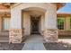 Close-up of the front entrance with a covered porch framed by stone pillars and a charming wooden door at 1443 N Poppy St, Casa Grande, AZ 85122