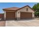 View of the house with a terracotta roof, neutral stucco, and a spacious three-car garage at 1443 N Poppy St, Casa Grande, AZ 85122