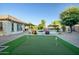 Spacious backyard featuring a putting green, sparkling pool, lush landscaping, and covered entertaining areas at 15803 W Almeria Rd, Goodyear, AZ 85395