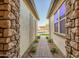 Inviting entranceway featuring a brick path, decorative trellises, and stone wall accents at 15803 W Almeria Rd, Goodyear, AZ 85395
