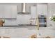 Elegant kitchen featuring a gas cooktop, marble countertops, stainless hood, and stylish gold fixtures at 15803 W Almeria Rd, Goodyear, AZ 85395