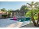 Relaxing pool area with lush palm trees, travertine tile, and covered patio with a cozy fire feature at 15803 W Almeria Rd, Goodyear, AZ 85395