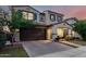 Beautiful two-story house with a brick driveway, manicured lawn, and a charming front porch with outdoor seating at 20576 W Briarwood Dr, Buckeye, AZ 85396