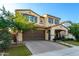 Attractive two-story home featuring a brick driveway, well-maintained lawn, and a charming front porch with outdoor furniture at 20576 W Briarwood Dr, Buckeye, AZ 85396