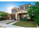 Two-story home boasts a brick driveway, green lawn, and a welcoming front porch with outdoor seating and colorful plants at 20576 W Briarwood Dr, Buckeye, AZ 85396