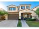 Lovely two-story home with a brick driveway, manicured lawn, and an inviting front porch with decorative plants and furniture at 20576 W Briarwood Dr, Buckeye, AZ 85396