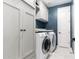 Laundry room with front load washer and dryer, white cabinets, blue walls, and tile floors at 20576 W Briarwood Dr, Buckeye, AZ 85396