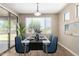 A bright, virtual staged dining area with a white table, four blue chairs, a window, and sliding glass doors to the exterior at 2116 W Fawn Dr, Phoenix, AZ 85041