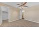 Bedroom features neutral carpet, ceiling fan with lighting and open walk-in closet and door to another room at 29368 N Red Finch Dr, San Tan Valley, AZ 85143