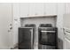 Modern laundry room includes a front-loading washer and dryer with white cabinetry above at 295 N Rural Rd # 133, Chandler, AZ 85226