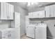 Functional laundry room with ample cabinet space, modern washer, and dryer for convenient chores at 3102 W Betty Elyse Ln, Phoenix, AZ 85053