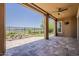 Expansive covered patio featuring stone flooring, ceiling fan, and views of the meticulously landscaped backyard and golf course beyond at 36172 N Secret Garden Path, Queen Creek, AZ 85140