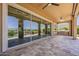 Undercover patio with large sliding glass doors, stone flooring, built-in grill, and views of the immaculate backyard and golf course at 36172 N Secret Garden Path, Queen Creek, AZ 85140