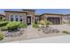 Charming single-story home featuring beautiful landscaping, a paver driveway, and an inviting entrance with a decorative iron door at 36172 N Secret Garden Path, Queen Creek, AZ 85140
