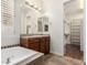 Bathroom featuring large soaking tub and a vanity with warm lighting, tile counter and wood cabinets at 4332 S Oregon Ct, Chandler, AZ 85248