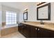 Bathroom featuring a soaking tub, dual sinks, granite countertops and framed mirrors at 5507 E Kings Ave, Scottsdale, AZ 85254