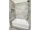 Bathroom featuring a gray tiled shower and tub combo with neutral fixtures at 7321 N 123Rd Dr, Glendale, AZ 85307
