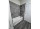 Bathroom featuring a gray tiled shower and tub combo with neutral fixtures at 7321 N 123Rd Dr, Glendale, AZ 85307