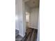 Hallway with gray wood flooring and white walls leading to a bedroom with carpet at 7321 N 123Rd Dr, Glendale, AZ 85307