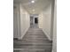 Long hallway featuring gray wood-look flooring, leading into the open-concept kitchen and living spaces at 7321 N 123Rd Dr, Glendale, AZ 85307