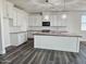 Bright kitchen with white cabinets, granite countertops, a large island and modern lighting fixtures at 7321 N 123Rd Dr, Glendale, AZ 85307