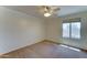 Bedroom has cozy carpeting, a ceiling fan, and a sunny window offering neighborhood views at 7398 W Paso Trl, Peoria, AZ 85383