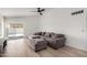 A spacious living room with a ceiling fan, wood floors and a sectional sofa with an ottoman at 8835 W John Cabot Rd, Peoria, AZ 85382