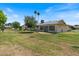 Large backyard featuring lush green grass, mature shade trees and a glimpse of palm trees at 10895 W Clair Dr, Sun City, AZ 85351