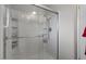 A bright and white stand-up shower featuring built-in storage and a clear glass door at 10895 W Clair Dr, Sun City, AZ 85351
