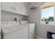 Functional laundry room with side-by-side washer and dryer, storage cabinets and window at 10895 W Clair Dr, Sun City, AZ 85351