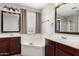 Bathroom with soaking tub, dual sinks, dark wood cabinets, and glass block window at 11724 N 148Th Ave, Surprise, AZ 85379