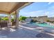 Inviting backyard oasis boasts a covered patio and a sparkling swimming pool with a small waterfall at 13824 W Gelding Dr, Surprise, AZ 85379