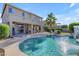 Inviting backyard oasis boasts a covered patio and a sparkling swimming pool with a small waterfall at 13824 W Gelding Dr, Surprise, AZ 85379