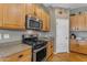 Modern kitchen with stainless steel appliances, wooden cabinets, and a granite countertop, ready for culinary adventures at 13824 W Gelding Dr, Surprise, AZ 85379