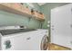 Functional laundry room features a washer, dryer, storage, shelving, and a convenient exterior door at 13824 W Gelding Dr, Surprise, AZ 85379