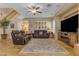 Spacious living room with a ceiling fan, plantation shutters, and leather reclining sofas at 13824 W Gelding Dr, Surprise, AZ 85379