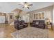 Open floor plan living room with tile floors, leather sofas, and a staircase at 13824 W Gelding Dr, Surprise, AZ 85379