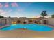 Inviting pool with basketball hoop and waterfall feature surrounded by desert landscaping and bathed in the glow of twilight at 13824 W Gelding Dr, Surprise, AZ 85379