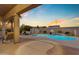 Backyard pool with waterfall feature, covered patio, and desert landscaping at 13824 W Gelding Dr, Surprise, AZ 85379