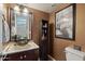 Stylish half bathroom with a modern vessel sink, decorative mirror, and unique artwork, adding a touch of elegance at 14517 W Cortez St, Surprise, AZ 85379