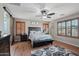 This main bedroom features wood floors, a ceiling fan, shutters, and a rustic wood accent sliding door at 14517 W Cortez St, Surprise, AZ 85379