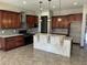 Well-lit kitchen featuring wooden cabinets, mosaic backsplash, stone countertops and large island with dark pendant lighting at 15625 N Jerry St, Surprise, AZ 85378