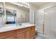 Well-lit bathroom featuring a shower, a single sink vanity, and a large mirror reflecting the bedroom at 17317 N Ponca Way, Surprise, AZ 85374