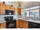 Kitchen area with black appliances, light wooden cabinets, and stainless-steel double sink at 17317 N Ponca Way, Surprise, AZ 85374